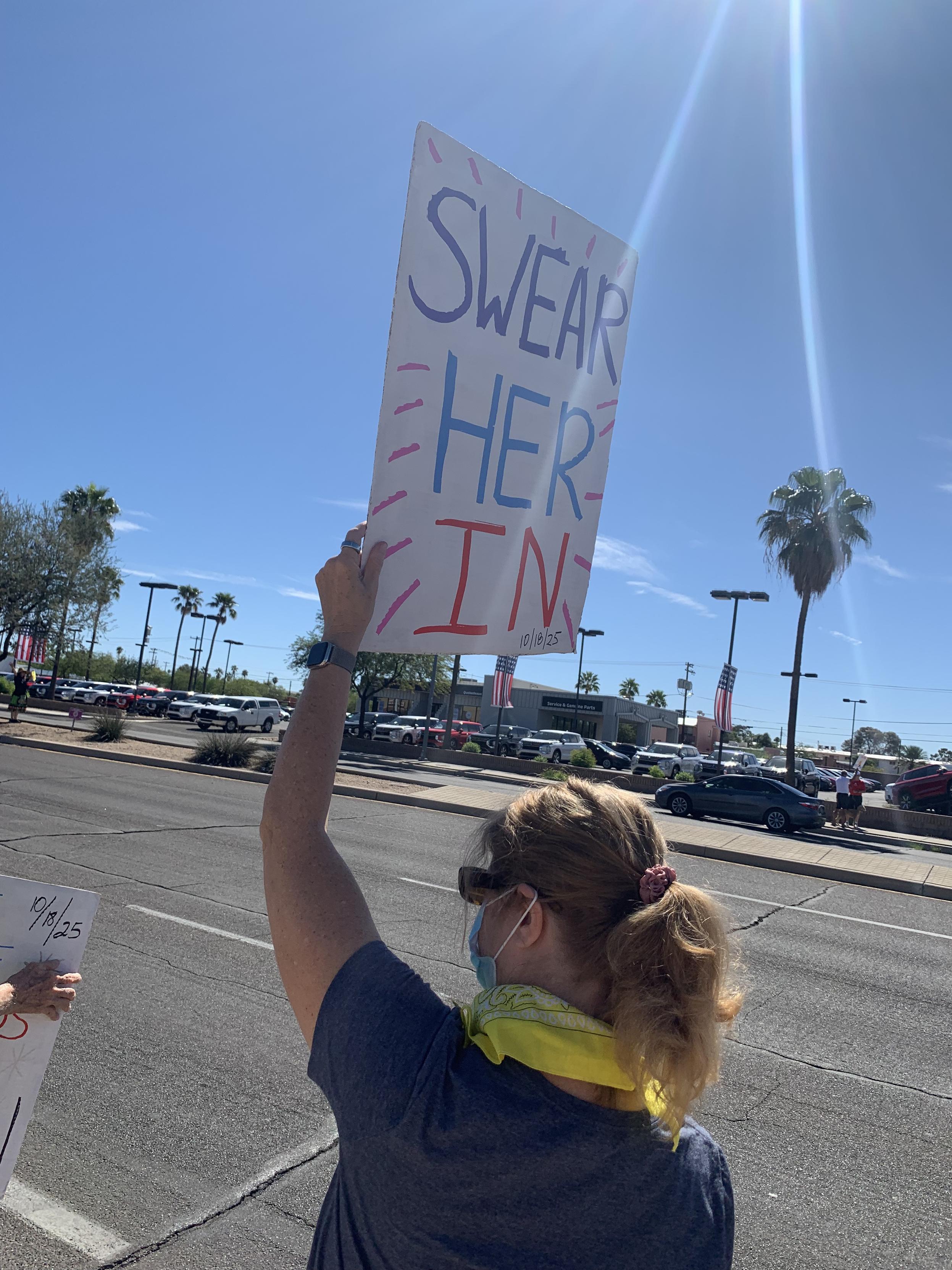 Protestor holding "Swear her in" sign