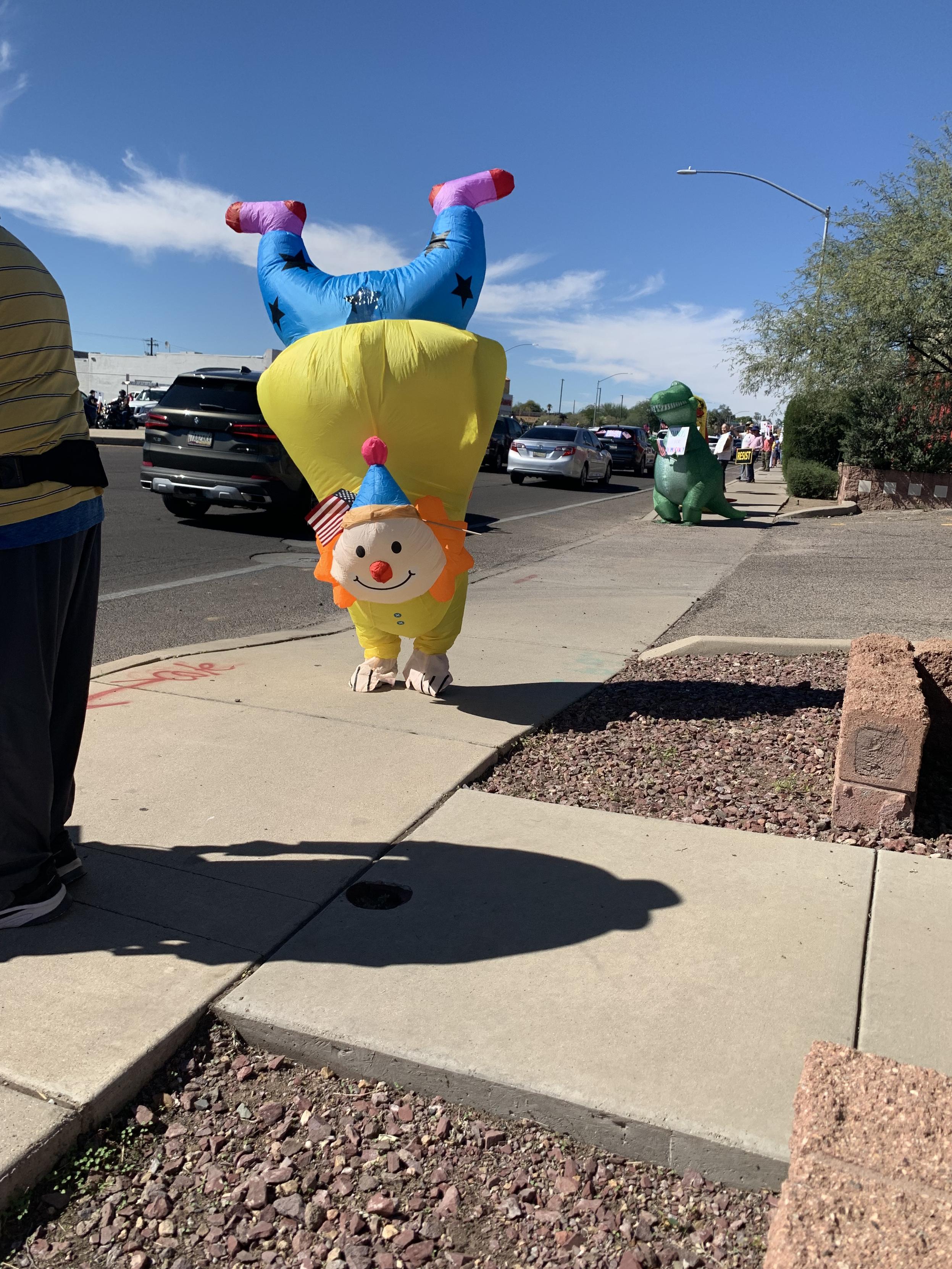 Inflatable costume of a clown walking in a handstand, walking along a sidewalk