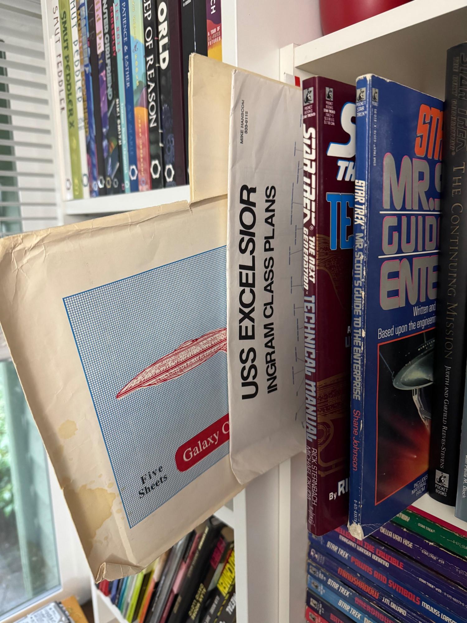 A portion of my bookshelf, with blueprints for the Enterprise-D and Excelsior, the TNG Technical Manual, and Mr. Scott's Guide to the Enterprise pulled out to be more visible.